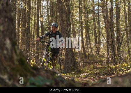 Frau lächelt Mountainbiking im Wald Stockfoto