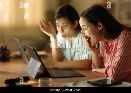 Verblüffte Telearbeiter, die in der Nacht zu Hause ihren Laptop überprüfen Stockfoto