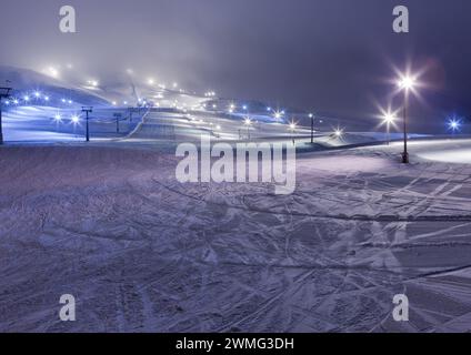 Eine verschneite Landschaft mit Lichtern und Skiliftwegen Stockfoto