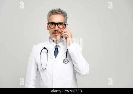 Ein leitender Arzt wird während des Gesprächs am Telefon dargestellt und zeigt die dynamischen und reaktionsschnellen Aspekte moderner Gesundheitspraktiken. Stockfoto