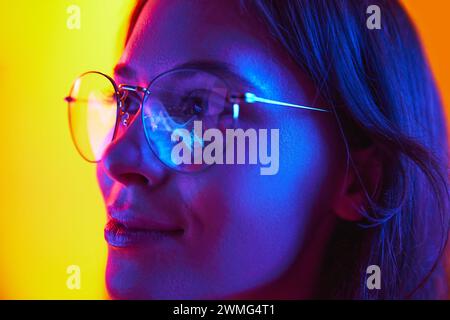 Nahporträt einer jungen Geschäftsfrau in Brille, die im Büro am Laptop arbeitet, Reflexion des Computerbildschirms in der Brille. Stockfoto