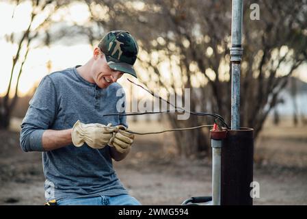 Nahaufnahme eines lächelnden Mannes, während er draußen Elektroarbeiten verrichtet Stockfoto