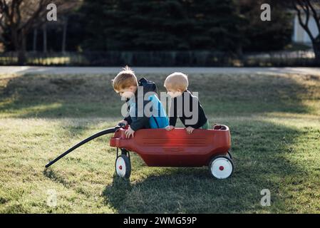 Voller Blick auf zwei Jungs, die in einem roten Wagen zu Hause sitzen. Stockfoto