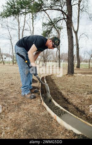 Seitenansicht eines Mannes, der im Hof Beton in Formen gießt Stockfoto