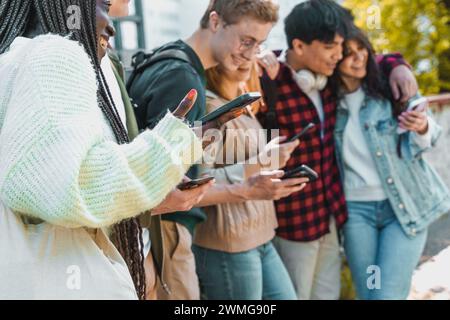 Gruppe von Freunden, die Smartphones nutzen – Interaktion in sozialen Medien – Konnektivität, Teilen, Jugend, Freizeit im Freien. Stockfoto