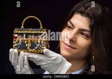 London, Großbritannien. 26. Februar 2024. Ein Mitarbeiter mit einer Judith Leiber: Gold „Sunken Treasure Chest“ Clutch Bag, 2022, (Est. £600 - £800) bei einer Vorschau auf Bonhams bevorstehende Designer Handtaschen und Fashion Sale. Luxuriöse Handtaschen und Ready-to-Wear-Designs werden am 28. Februar in den Bonhams Knightsbridge Galeries versteigert. Quelle: Stephen Chung / Alamy Live News Stockfoto