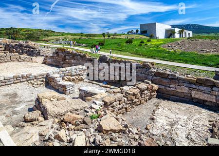 Dieses Bild fängt die antiken Ruinen der archäologischen Stätte Baelo Claudia im Vordergrund ein, während Besucher die historischen Wunder erkunden. In Th Stockfoto