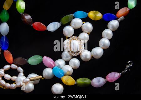 Farbsteine und Perlenkette (verschiedene Größen weiß und rosa Farbe) und rinf-Feinfinger (für Finger) mit Perle und kubischem Zirkonia (Glas?) Hat mich gemacht Stockfoto