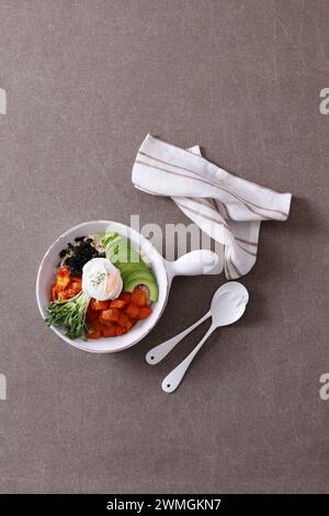 Koreanisches Essen. Lachs Poke Schüssel mit Avocado, Rucola und pochiertem Ei. Stockfoto