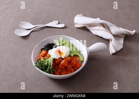 Koreanisches Essen. Lachs Poke Schüssel mit Avocado, Rucola und pochiertem Ei. Stockfoto