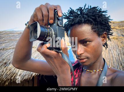 Ein junger Maasai-Krieger nutzt eine Leica M10-R Digitalkamera in seinem Dorf in Mikumi, Tansania. Stockfoto