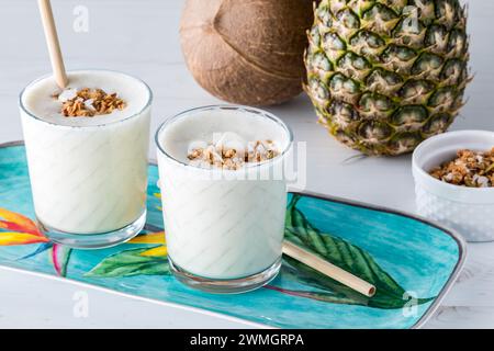 Ananas Kokos-Protein-Smoothies garniert mit Müsli und Kokos. Stockfoto