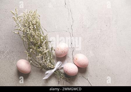 Rosafarbene Ostereier mit goldenen Flecken und gypsophila-Blumen auf grauem Steinhintergrund mit Kopierraum. Stockfoto