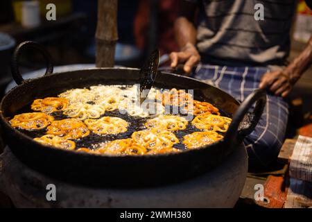 Ein indischer Ladenbesitzer bei Mela oder auf dem Land frittiert Süßigkeiten Jalebi in Öl Stockfoto