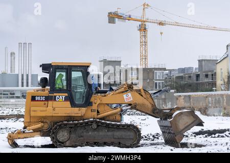 Nancy, Frankreich – Gelber Raupenlader CAT 963C für Erdarbeiten auf einer Baustelle unter Schnee mit einem Turmkran im Hintergrund. Stockfoto