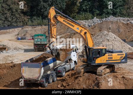 Nancy, Frankreich – Schwerpunkt auf einem gelben Raupenbagger Hyundai HX 330NL, der einen Lkw für Erdarbeiten auf einer Baustelle verlädt. Stockfoto