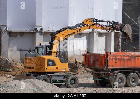 Nancy, Frankreich – Schwerpunkt auf einem gelben Radbagger Liebherr A 914 Compact, der einen Lkw für Erdarbeiten auf einer Baustelle verlädt. Stockfoto
