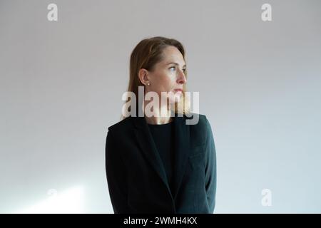 Porträt im Profil einer erwachsenen jungen Frau in einem schwarzen Anzug auf weißem Hintergrund. Stockfoto