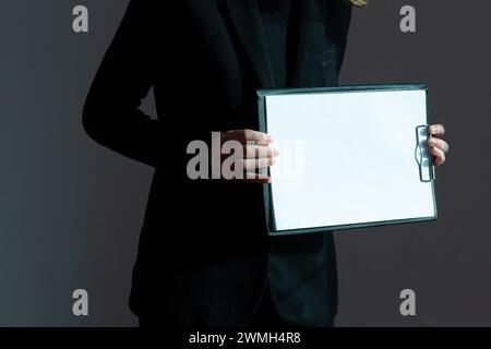 Ein weißes Blatt Papier auf einer Schreibtafel wird durch Sonnenlicht in den Händen einer Frau hell beleuchtet. Stockfoto