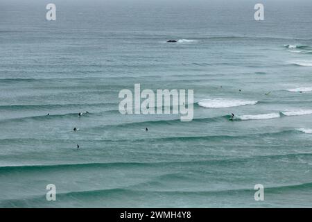 Surfer beobachten die Wellen des Pazifischen Ozeans vor Cape Byron in der Nähe des östlichsten Punktes des australischen Festlandes. Stockfoto