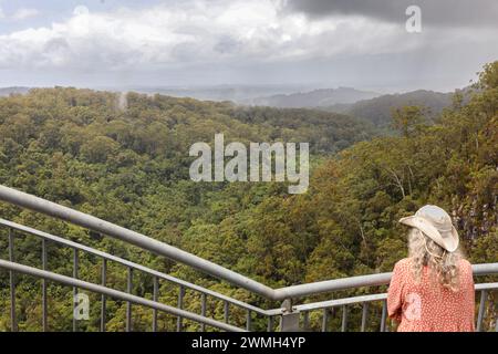 Eine Frau, die auf einer Abenteuertour rund um die Welt unterwegs ist, steht am Aussichtspunkt der Minyon Falls im Nightcap-Nationalpark in der Nähe von Alstonville, NSW, Australien. Stockfoto