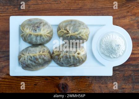 Manty mit Rindfleisch und Sauerrahm auf Holztisch Stockfoto