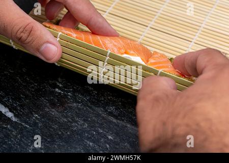 Der Mann, der zu Hause Sushi zubereitet, ein hausgemachtes Gourmet-Lachsbrötchen Stockfoto