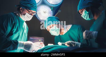 Professionelle Ärzte und Team, das chirurgische Operationen im hellen modernen Operationssaal mit Beleuchtungsgeräten im Krankenhaus durchführt. Stockfoto
