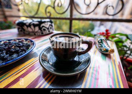 Ein schwarzer Becher auf dem Tisch vor dem Hintergrund der wunderschönen mittelalterlichen Architektur. Schwarzer Kaffee in einer usbekischen Tasse. Stockfoto