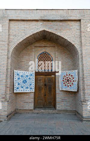 Kleine Teppiche hängen an der Wand vor dem Eingang zum Souvenirshop in Samarkand, Usbekistan. Stockfoto