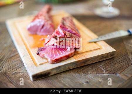 In Scheiben geschnittenes Tataki-Sirloin aus rotem Thunfisch auf einem Schneidebrett, fertig zum Servieren. Stockfoto