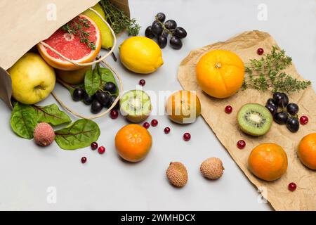 Früchte in Papiertüte. Persimmon, Kiwi und Orange auf dem Tisch. Grauer Hintergrund. Flache Lagen Stockfoto