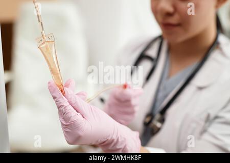 Nahaufnahme der Krankenschwester, die eine intravenöse Tropfbehandlung im Operationsraum im Kopierraum der Klinik einrichtet Stockfoto