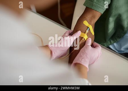 Nahaufnahme des Arztes, der den Patienten für einen Bluttest oder eine intravenöse Infusion vorbereitet und die Bandage auf den Arm-Kopierraum legt Stockfoto