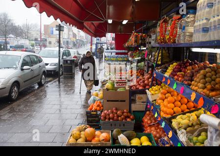 Eine Frau, die an einem Obst- und Gemüseladen an der Soho Road in Handsworth, Birmingham, vorbeifährt. Stockfoto