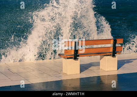 Eine Bank am welligen Meer Stockfoto