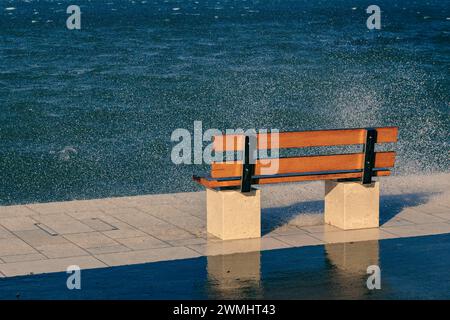 Eine Bank am welligen Meer Stockfoto