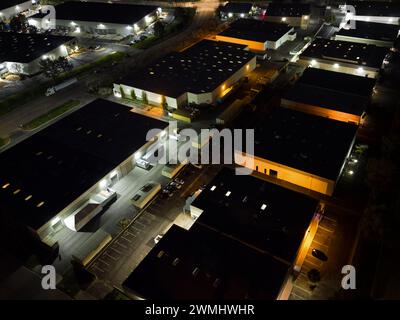 Unscheinbare Lagerhäuser und Bürogebäude eines Industrieparks werden nachts aus der Sicht von oben gezeigt. Stockfoto