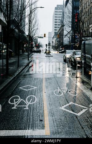 Ein Foto des Radweges auf der Dunsmuir Street an der Kreuzung mit der Granville Street an einem regnerischen Tag, auf dem die Fahrrad- und Diamantschilder zu sehen sind. Stockfoto