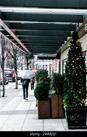 Ein Blick auf den Bürgersteig der Georgia Street gegenüber der Vancouver Art Gallery, an einem regnerischen Tag, wo Menschen Regenschirme tragen. Stockfoto