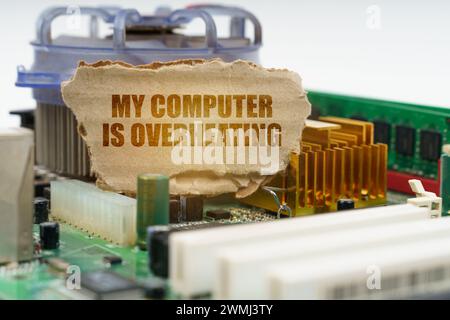 Auf der Hauptplatine des Computers befindet sich ein Karton mit der Aufschrift - mein Computer ist überhitzt. Computerreparaturkonzept. Stockfoto