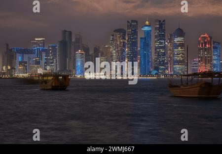 Doha, Katar Skyline von der Corniche Promenade bei Nacht mit Daus und Booten im arabischen Golf Stockfoto