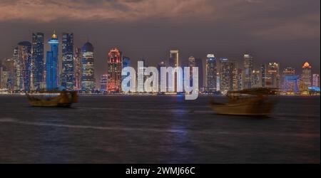 Doha, Katar Skyline von der Corniche Promenade bei Nacht mit Daus und Booten im arabischen Golf Stockfoto