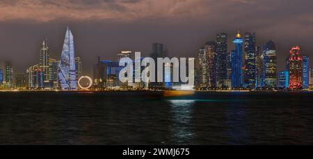 Doha, Katar Skyline von der Corniche Promenade bei Nacht mit Daus und Booten im arabischen Golf Stockfoto