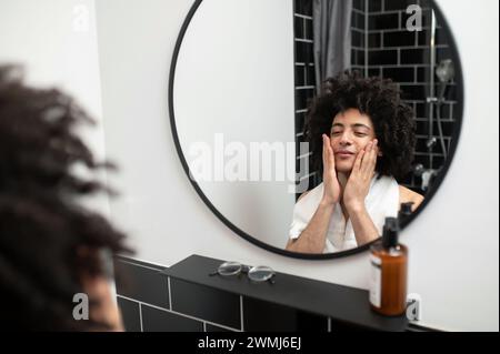 Brünette, lockiger Mann, der morgens im Bad operiert Stockfoto