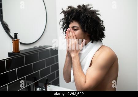 Brünette, lockiger Mann, der morgens im Bad operiert Stockfoto