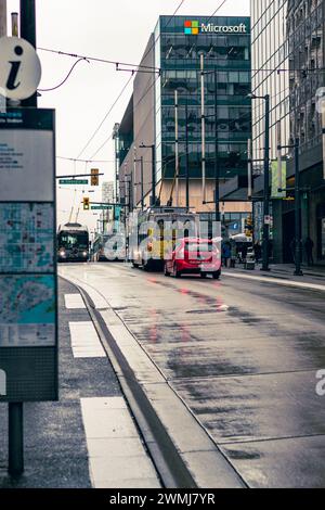 Vancouver, Kanada - 21. Februar 2024: Ein Blick auf die Granville Street an einem regnerischen Tag, ein hellrotes Taxi hinter einem Bus, das darauf wartet, die Georgia Street zu überqueren. Stockfoto