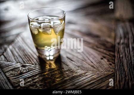 Ein Whiskey-Shot mit Eiswürfeln auf einer Holzoberfläche. Stockfoto