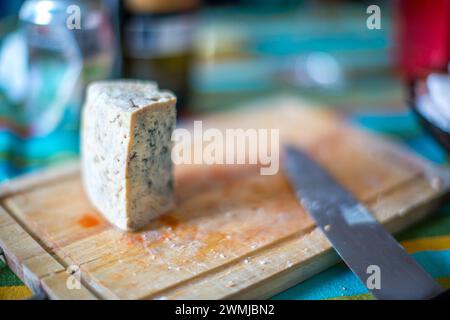 Ein Keil Cabrales Blaukäse steht auf einem Schneidebrett neben einem Messer. Stockfoto