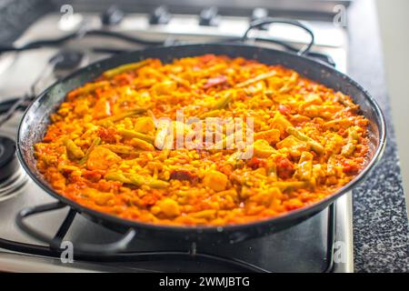 Eine Pfanne farbenfroher traditioneller spanischer Paella, die gekocht und serviert wird. Stockfoto